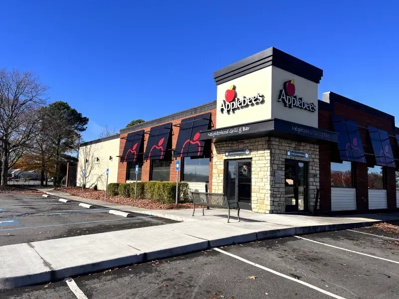 Applebee's restaurant exterior with black awnings, stone facade entrance, and clear blue sky.