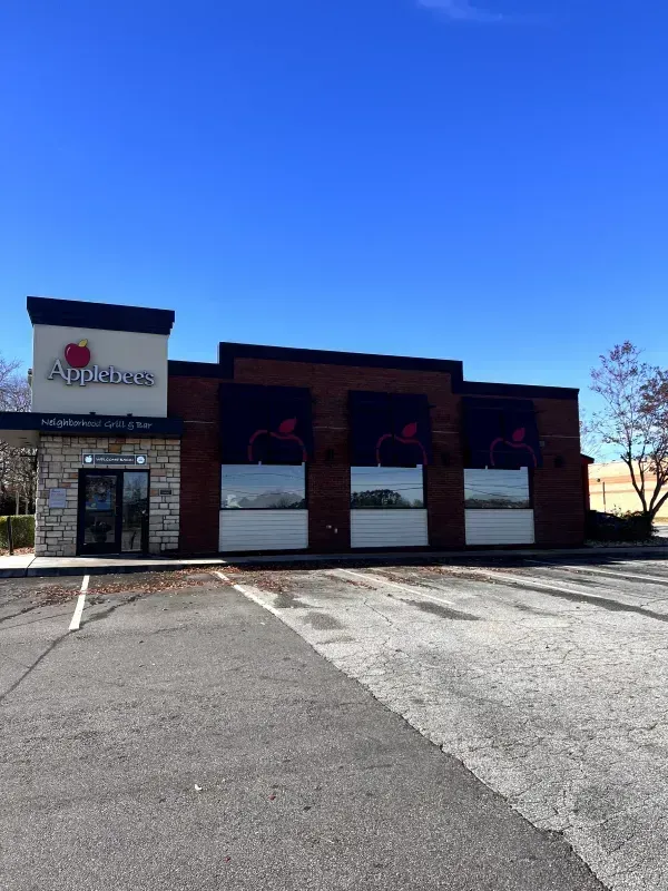 Applebee's restaurant building on a sunny day. Exterior view with parking lot and blue sky.