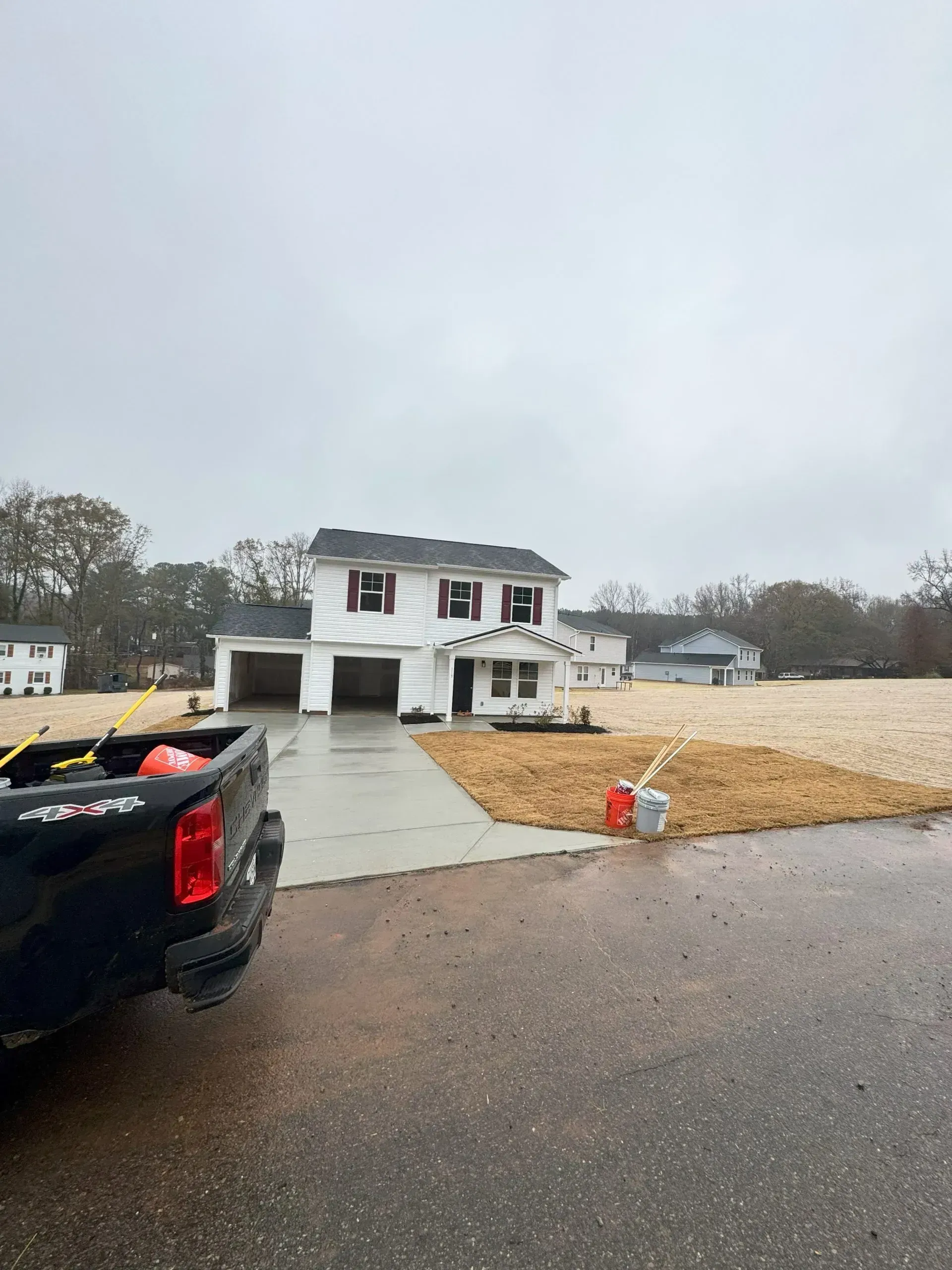 New house under construction on a rainy day, with a pickup truck in the foreground.