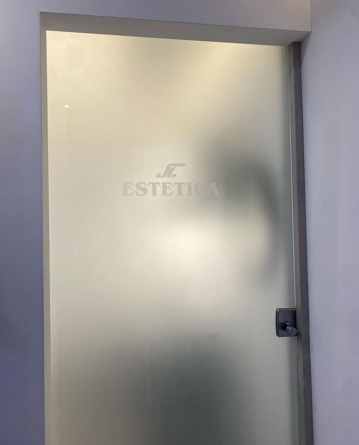 Una porta di vetro smerigliato con la parola estetica sopra