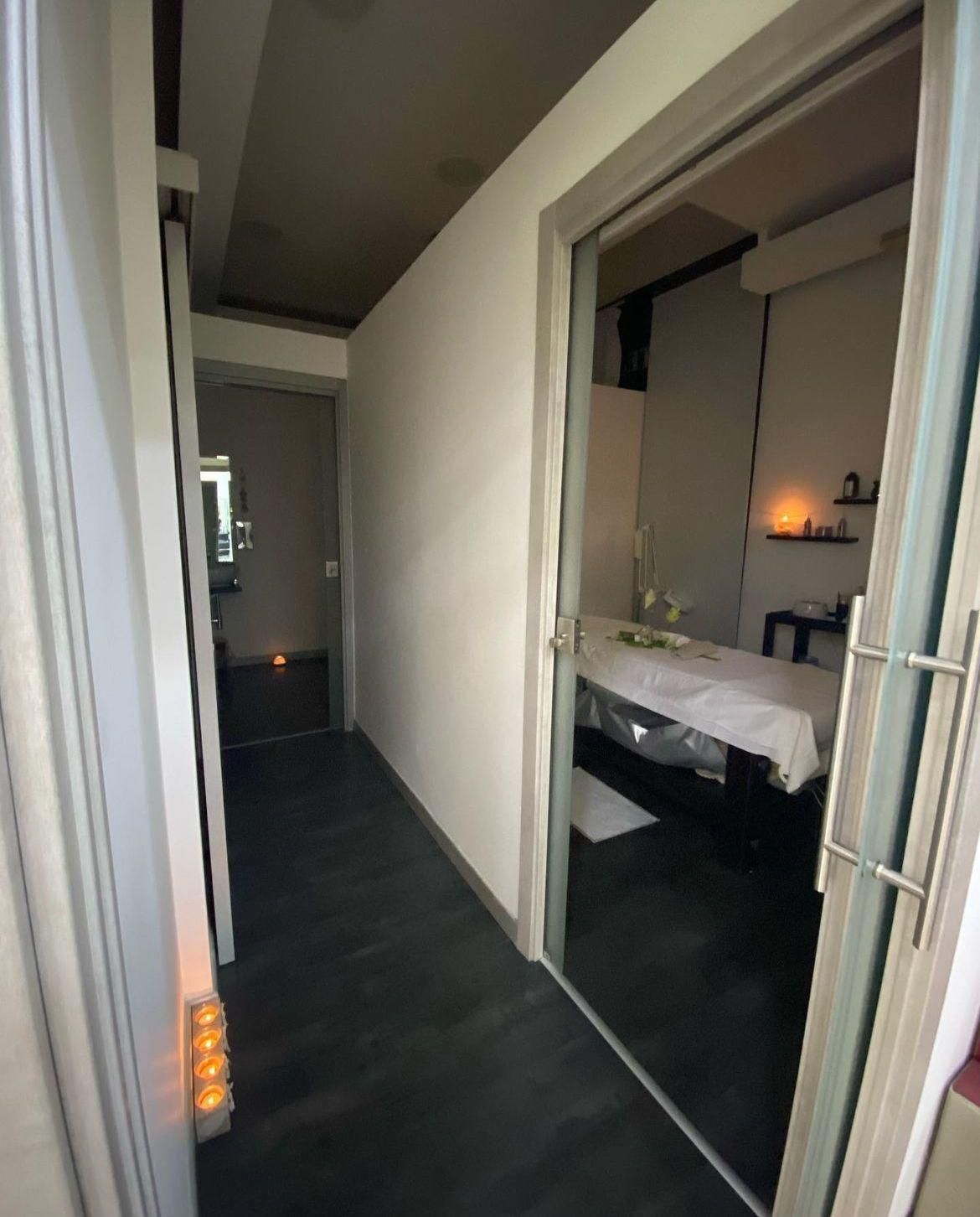 Un corridoio con una porta scorrevole in vetro che conduce a un lettino per massaggi