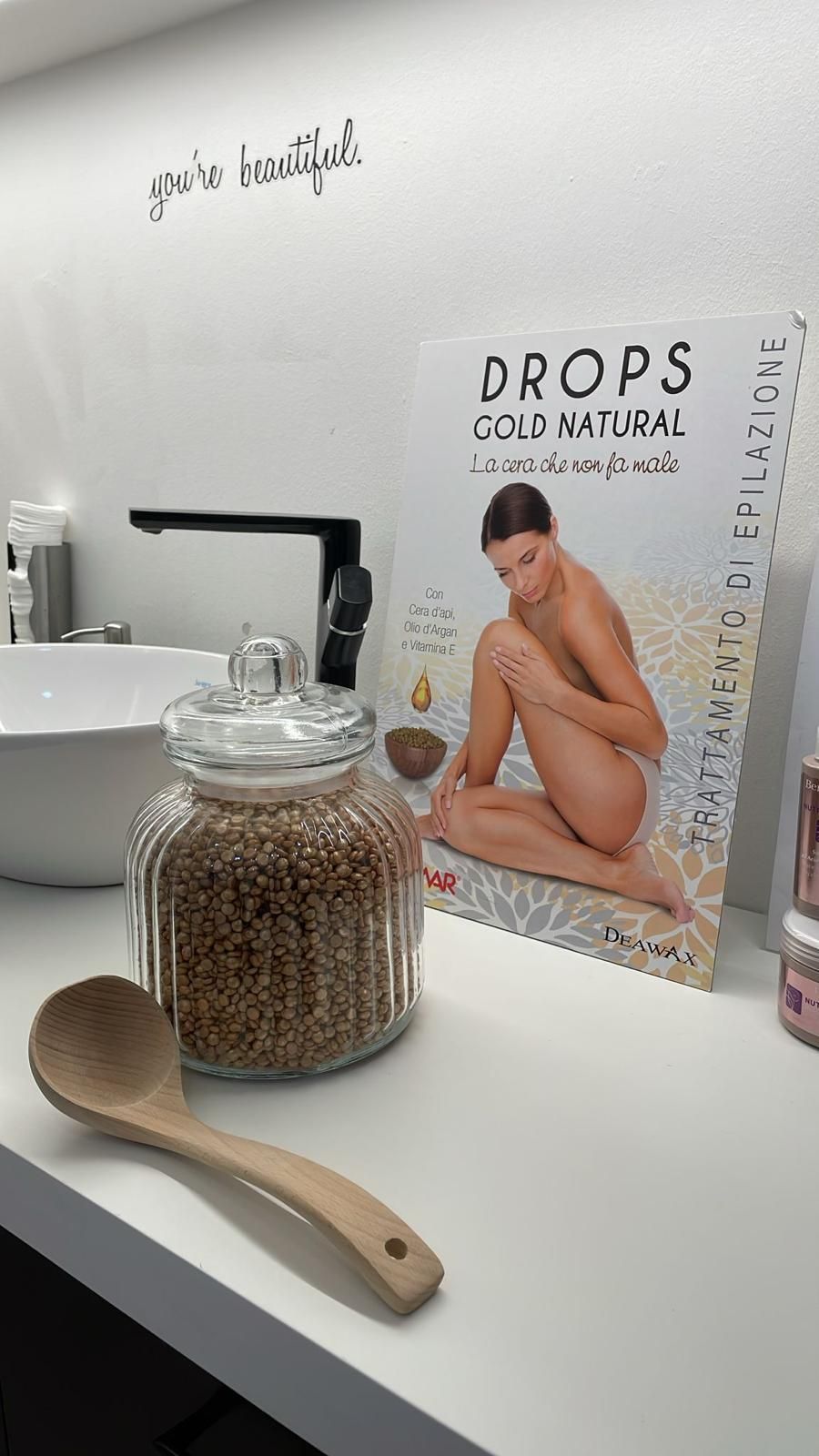 Un barattolo di gocce naturali fredde è appoggiato su un tavolo accanto a un cucchiaio di legno.