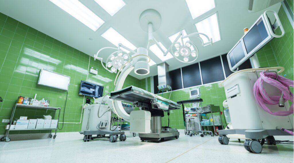 An empty operating room in a hospital with a surgical table and monitors.