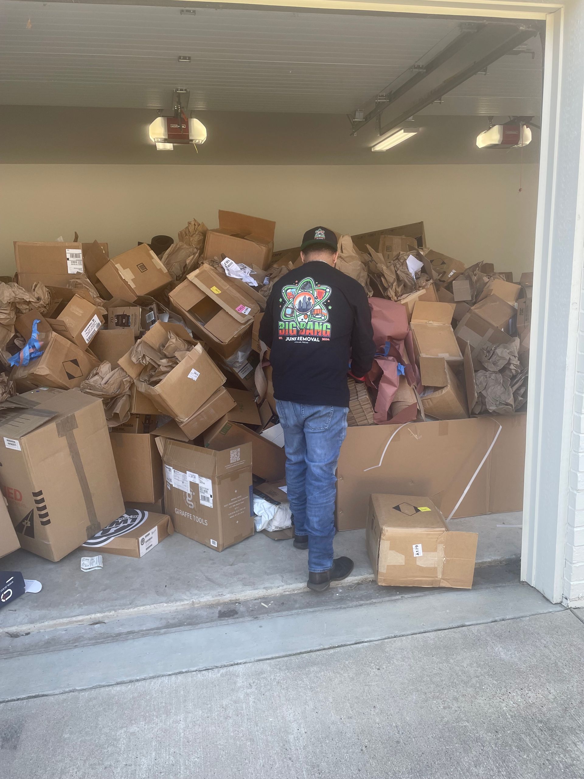 A man is standing in a garage filled with boxes.
