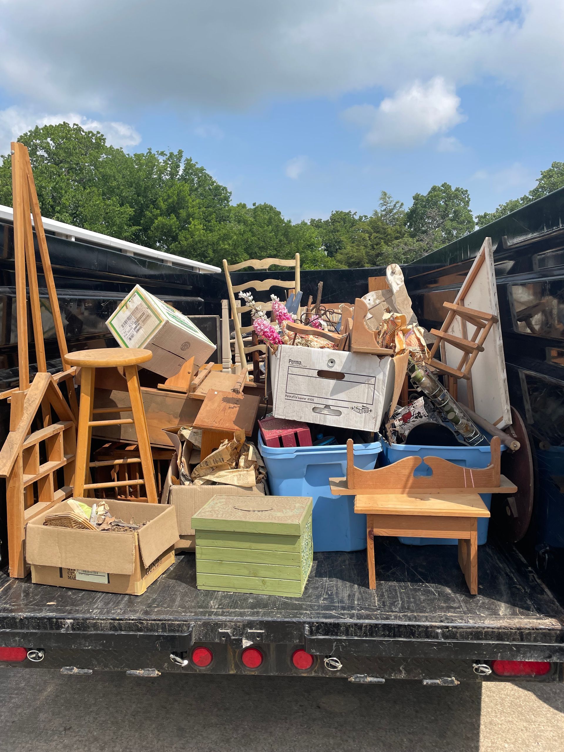 A dumpster filled with lots of furniture and boxes.