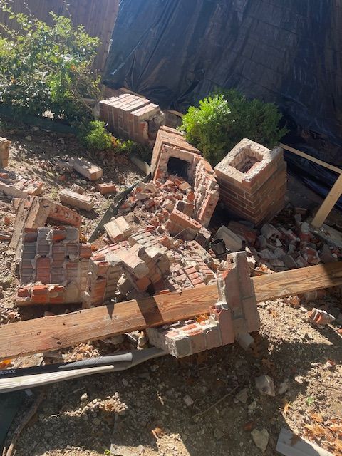 A pile of bricks and wood is laying on the ground.