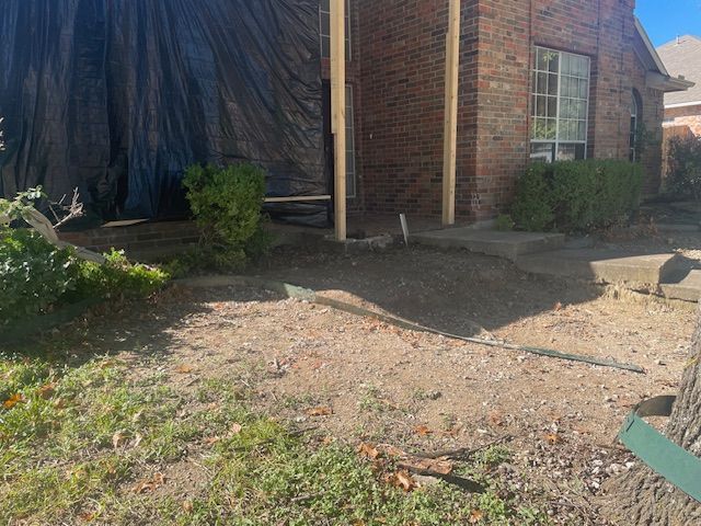 A brick house with a black tarp covering the front door.
