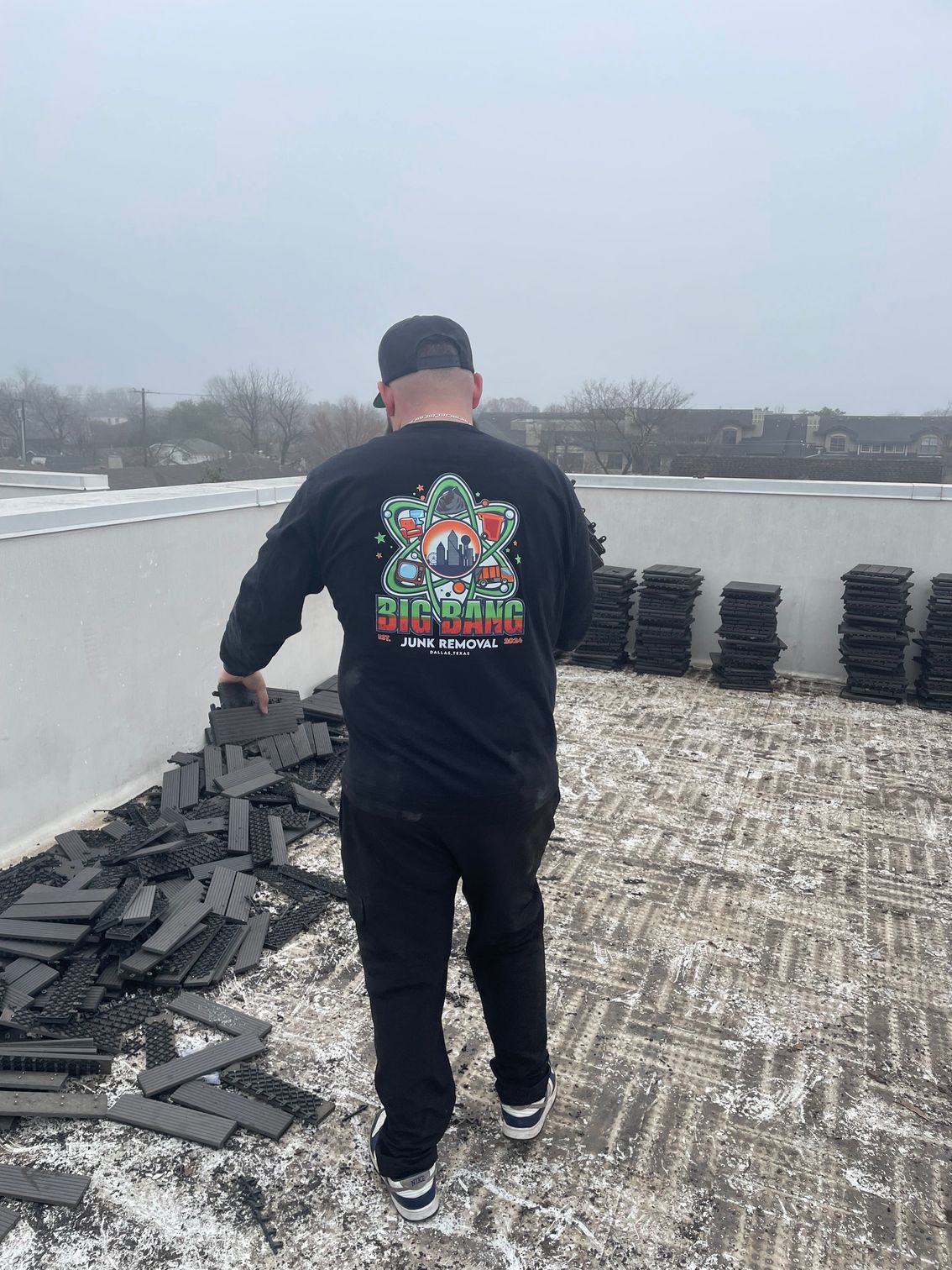 A man wearing a black shirt is standing on a roof.