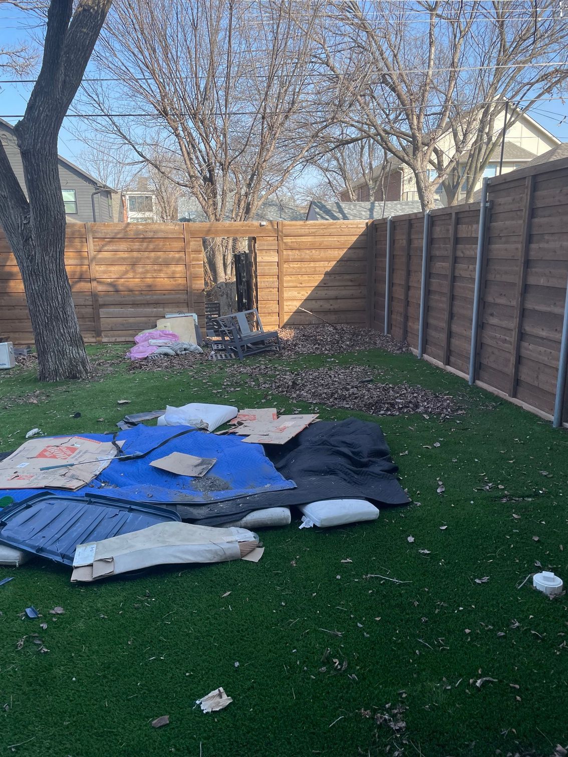 A bunch of cardboard boxes are laying on the grass in a backyard.