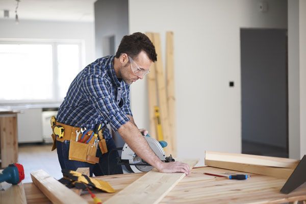 A man is cutting a piece of wood with a circular saw.