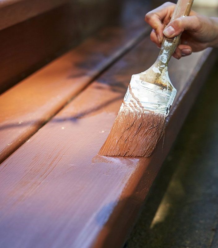 A person is painting a piece of wood with a brush