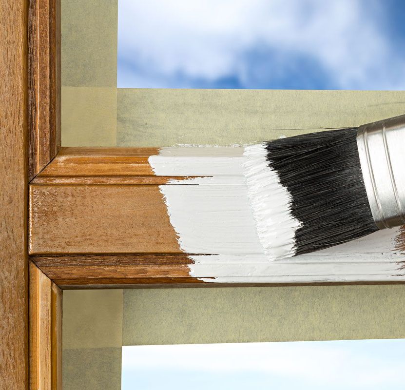 a person is painting a window frame with white paint