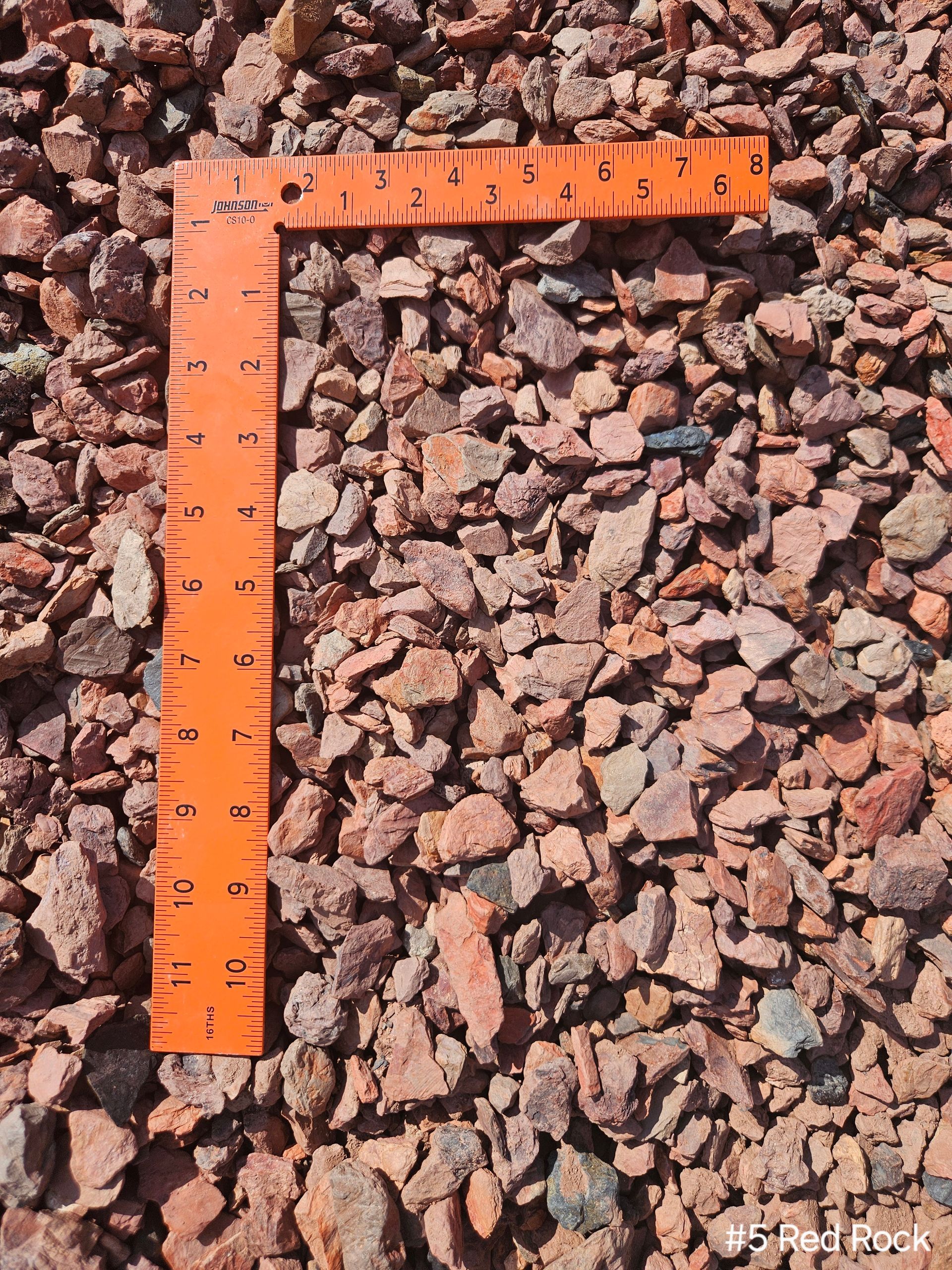 A gravel driveway going through a park with grass on both sides.