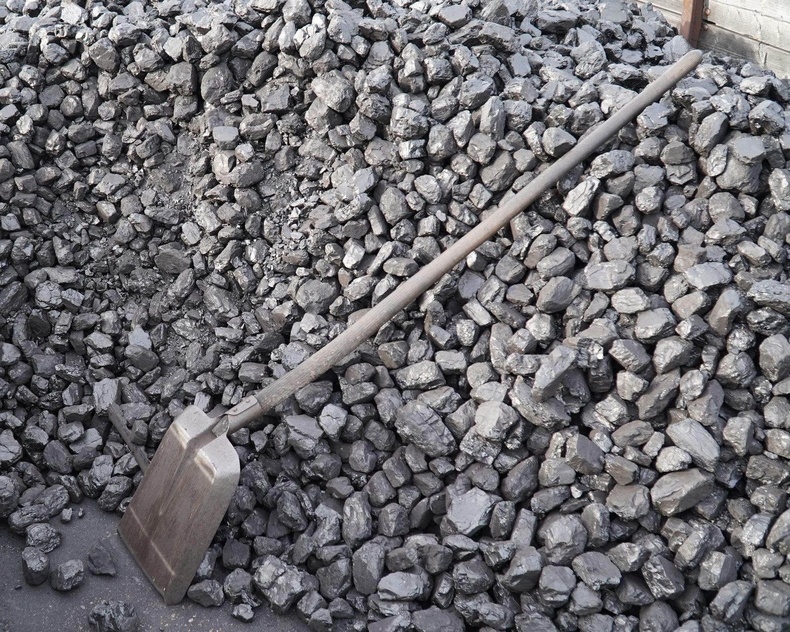 A gravel shovel is laid against a pile of construction stone.