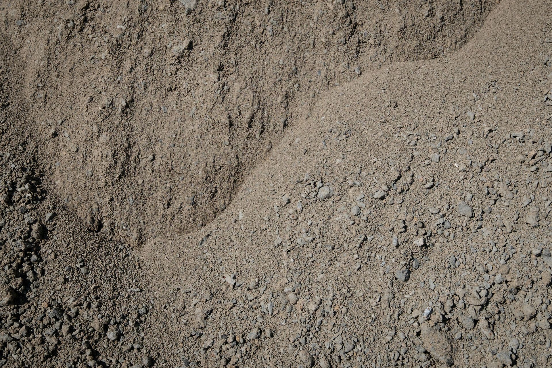 A pile of gravel is sitting on top of a pile of dirt.