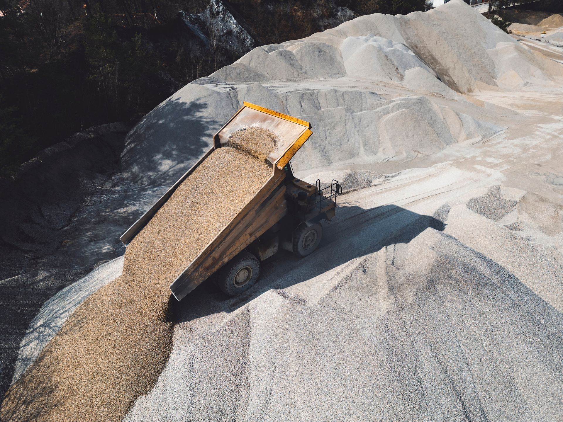 A dump truck is sitting on top of a pile of gravel.