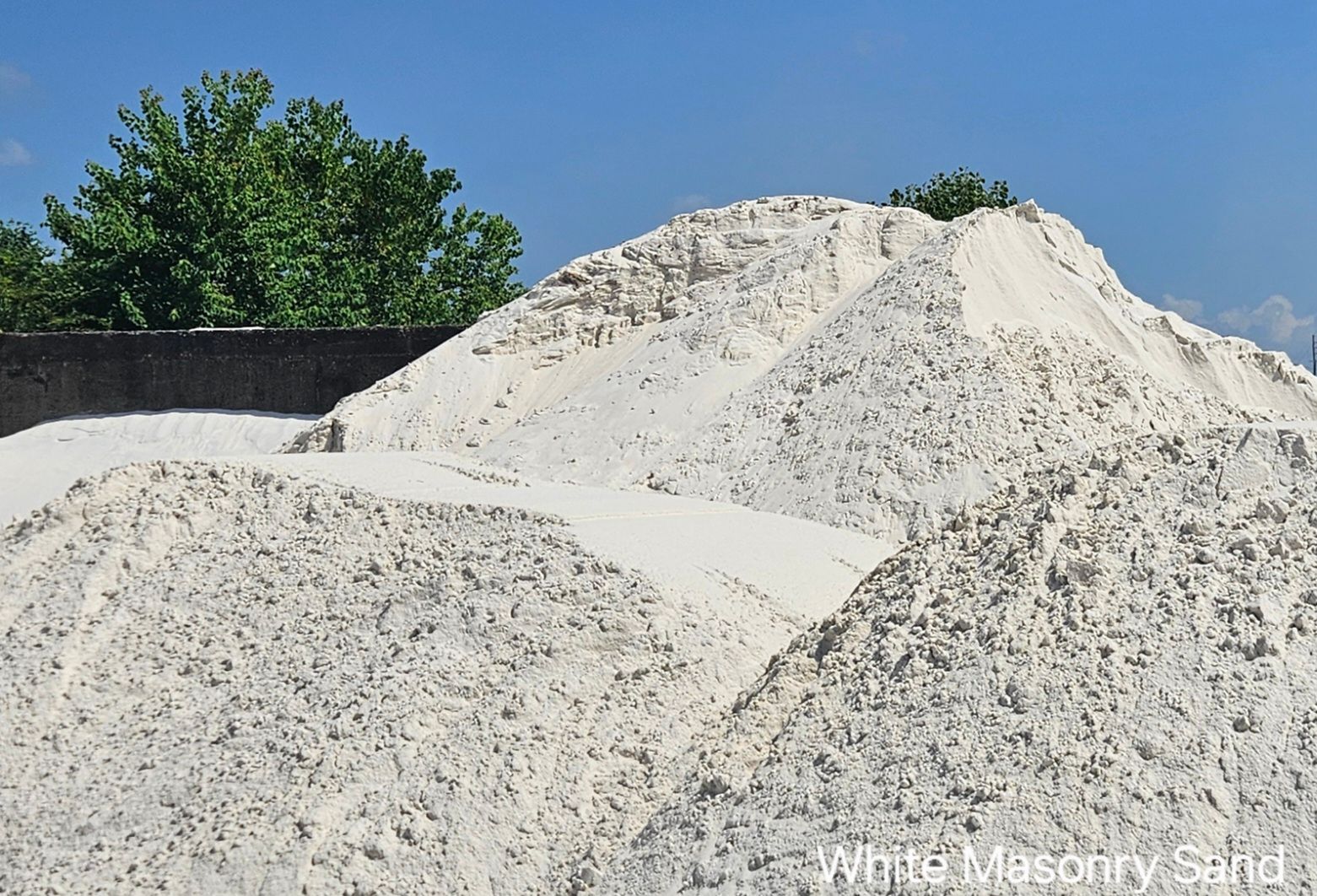 A gravel driveway going through a park with grass on both sides.