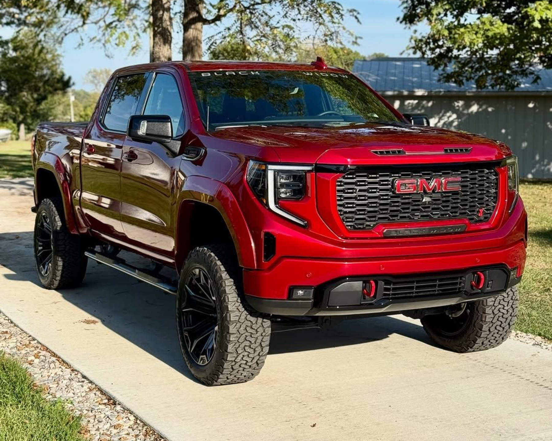 Red GMC Sierra truck parked on a concrete driveway with black rims and tires.