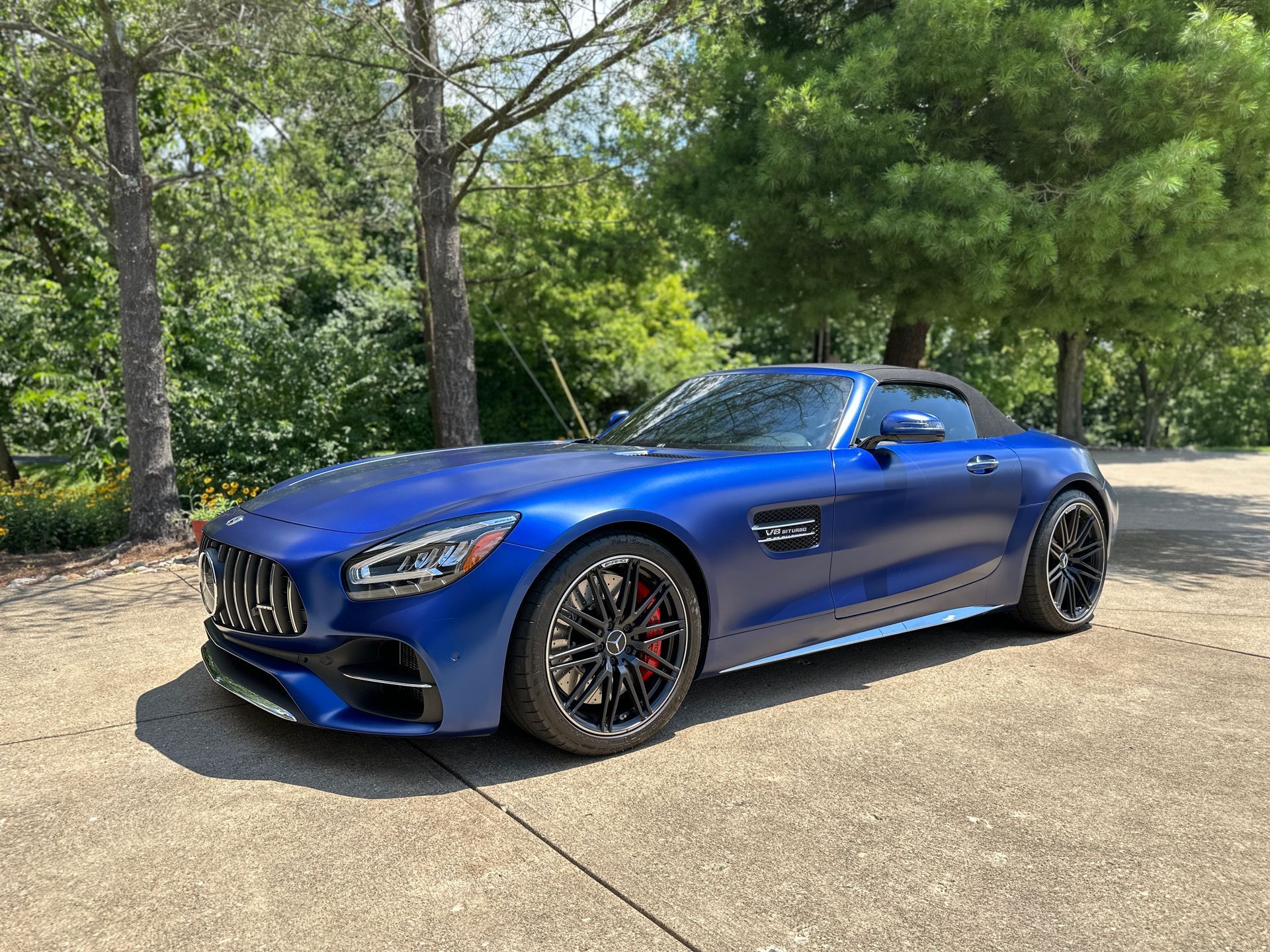 A blue mercedes amg gt convertible is parked in a driveway.