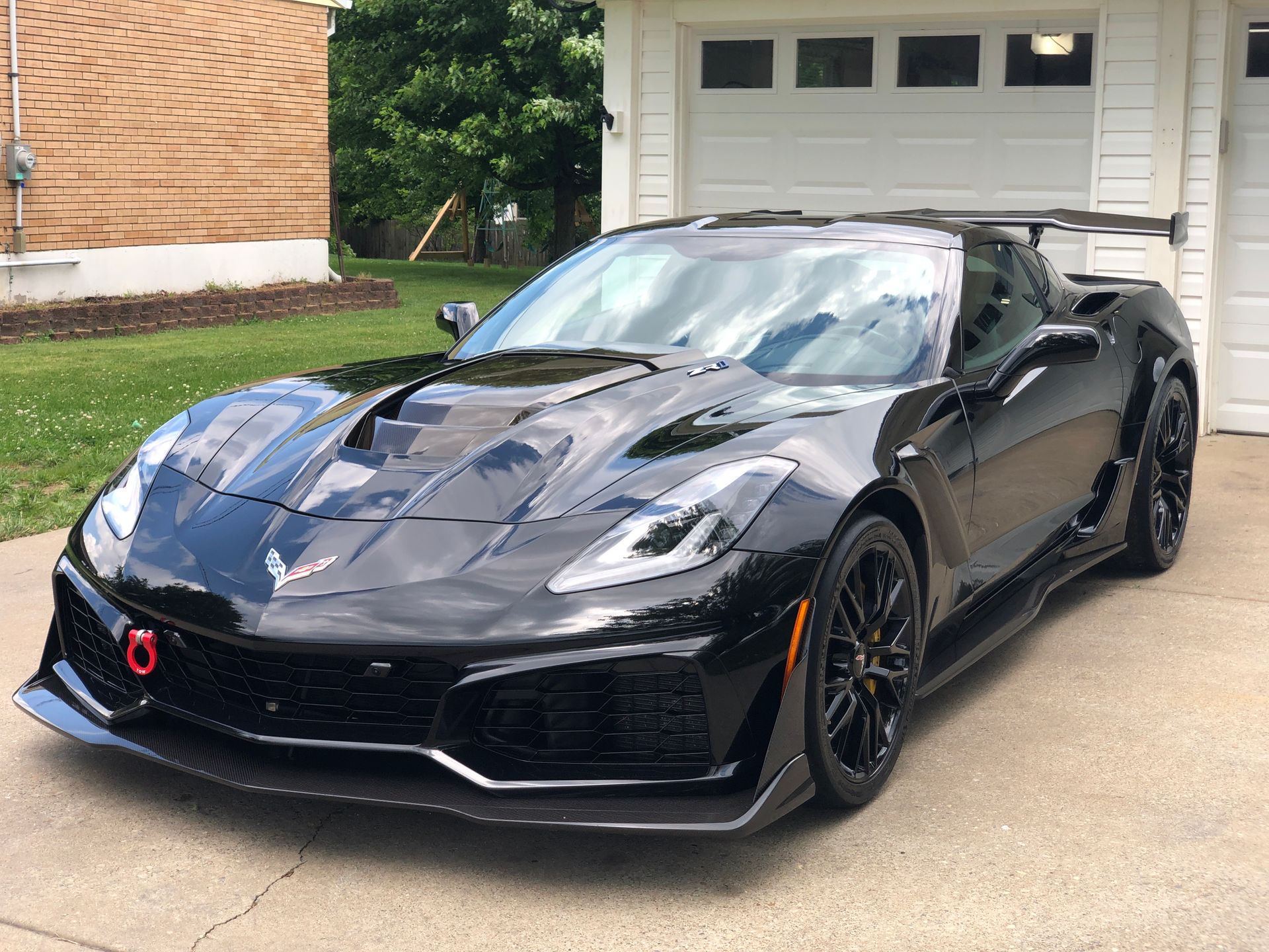 Black Chevrolet Corvette ZR1 sports car parked in front of a garage.