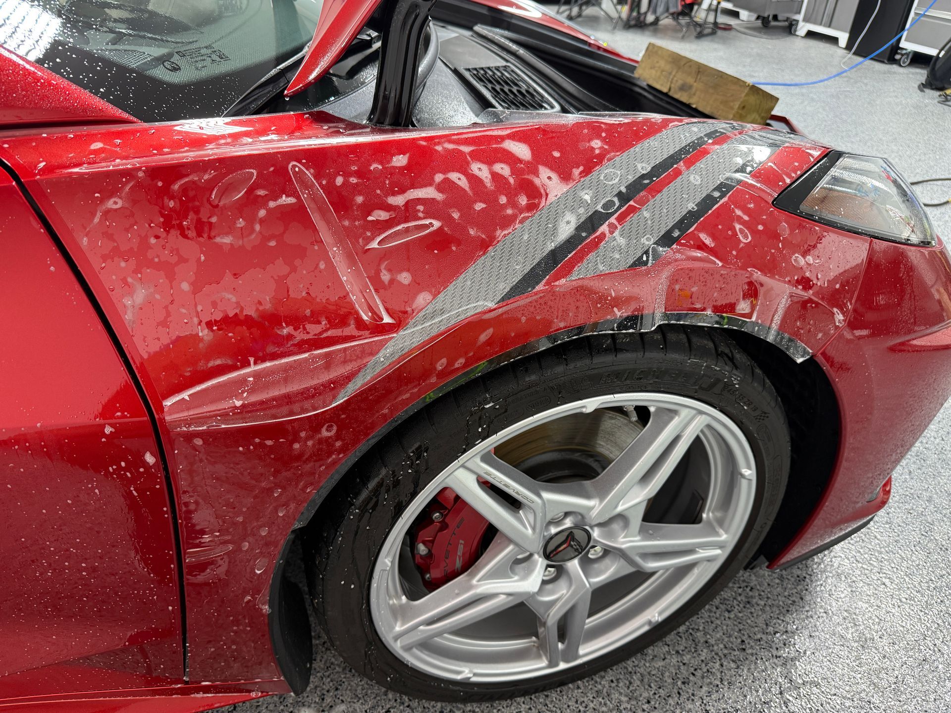 Red sports car with protective film applied to the front fender and bumper.