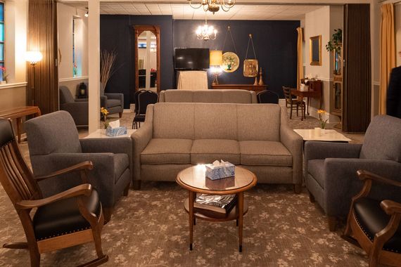 a wooden walkway leading to a gazebo overlooking a body of water at sunset .