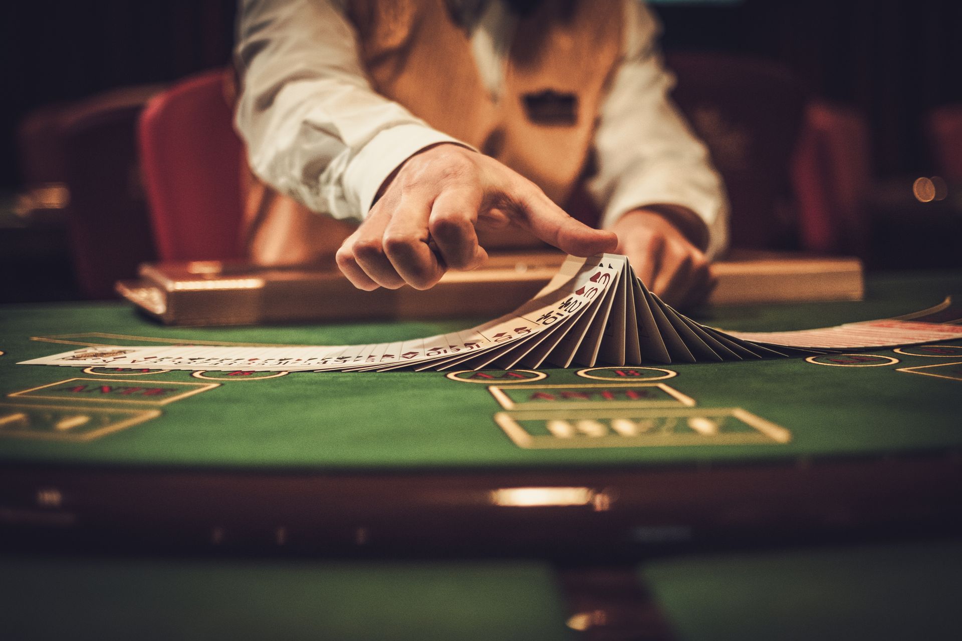 Dealer fanning cards on a green felt table in a casino.