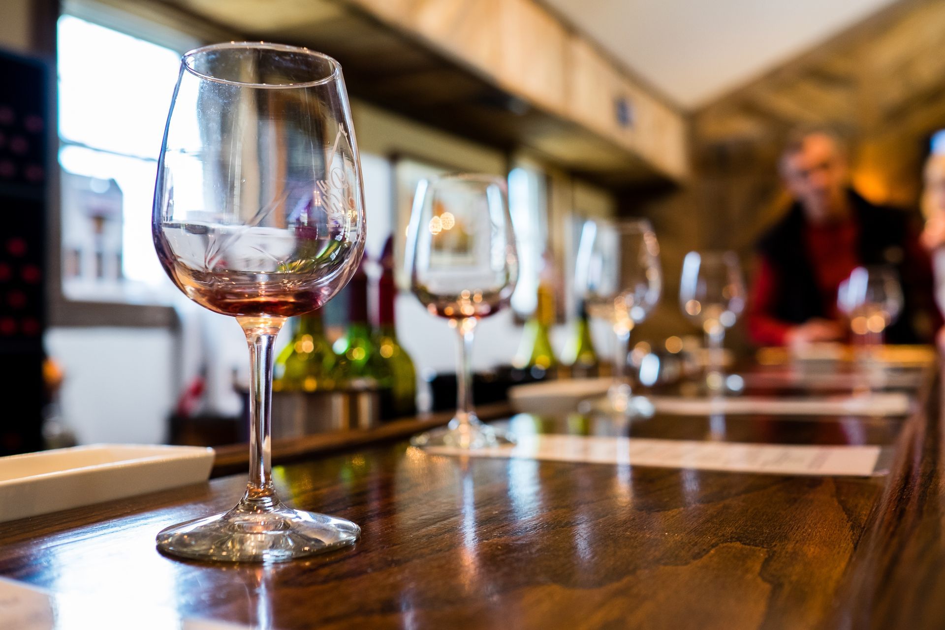 A row of wine glasses are sitting on a wooden table.
