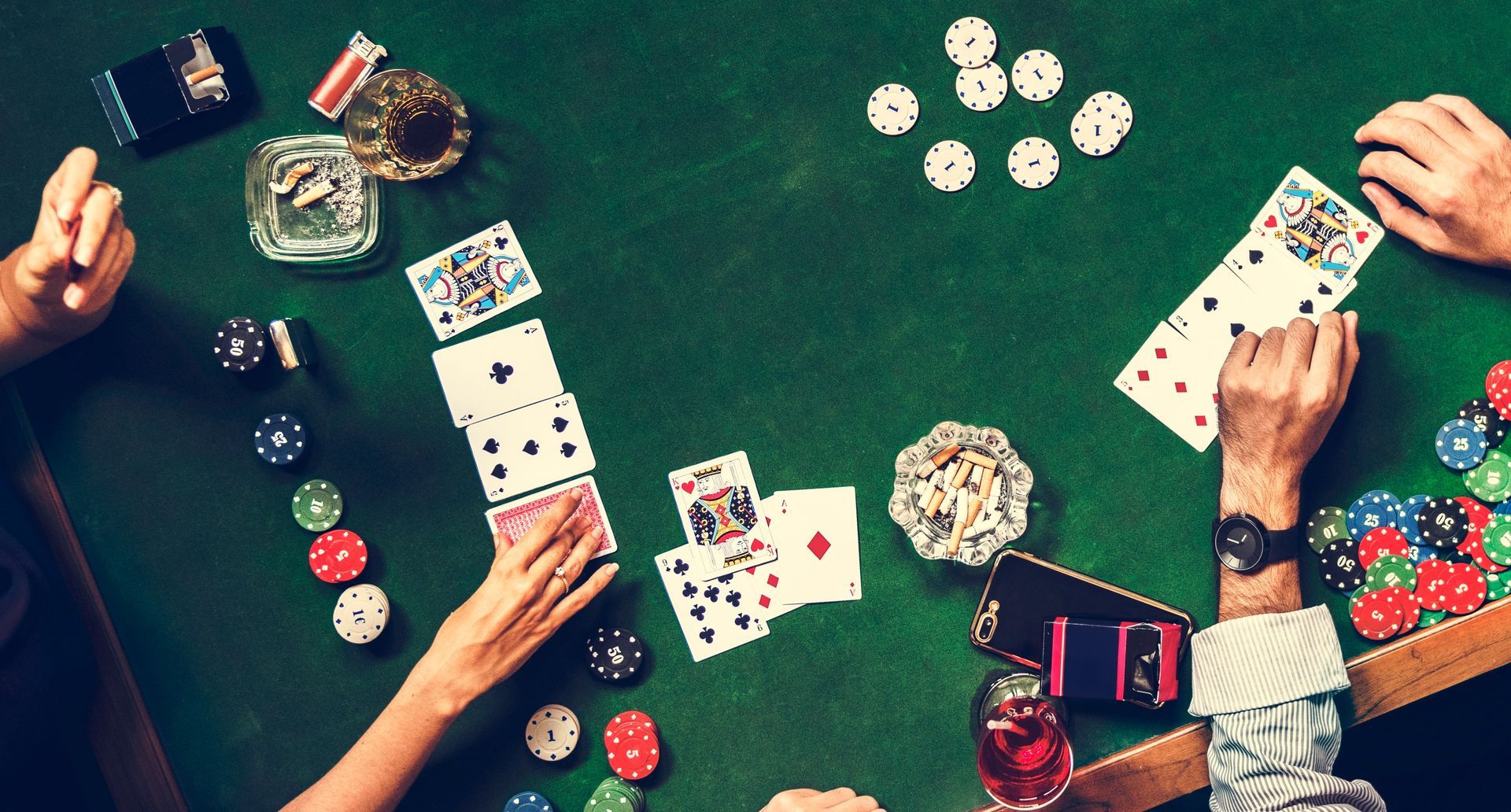 Poker game in progress; hands, cards, and chips on a green table.