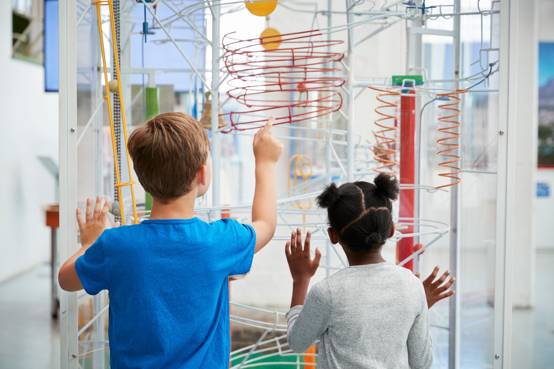 A boy and a girl are playing with a marble run in a museum.