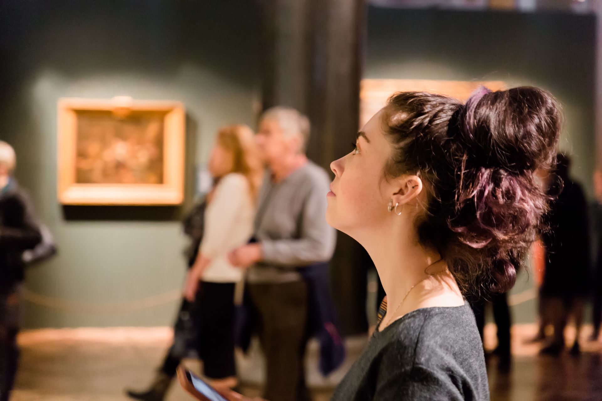 A woman is looking up at a painting in a museum.