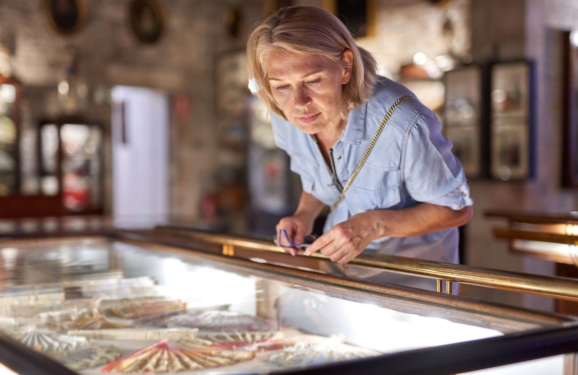 A woman is looking at a display case in a museum.