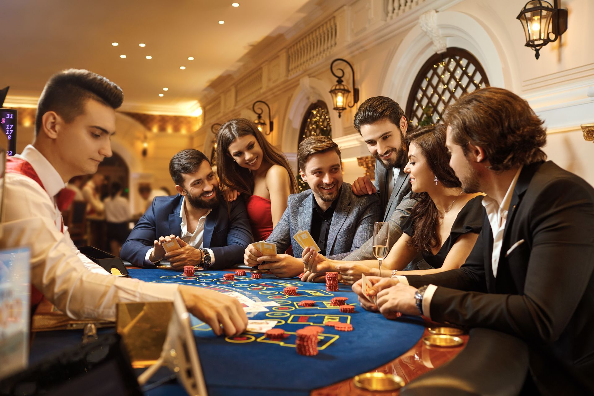 Group of people at a casino table, looking at cards. Chips and drinks present.
