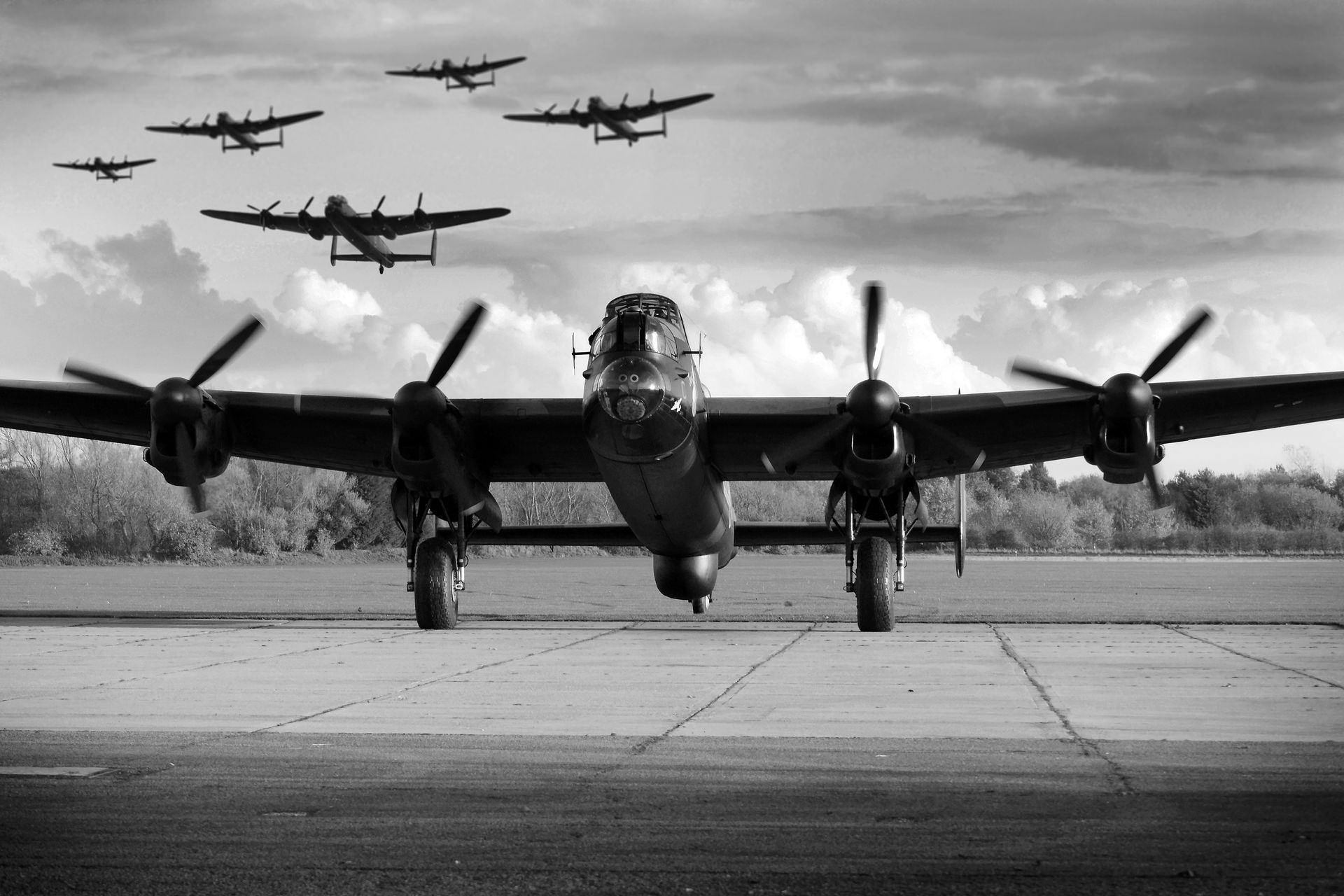 Black and white photo of a Lancaster bomber on a runway, with several others in the sky.
