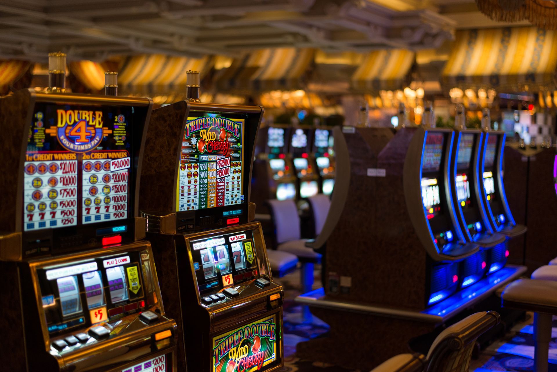 Slot machines in a casino, with colorful screens and blue lights.