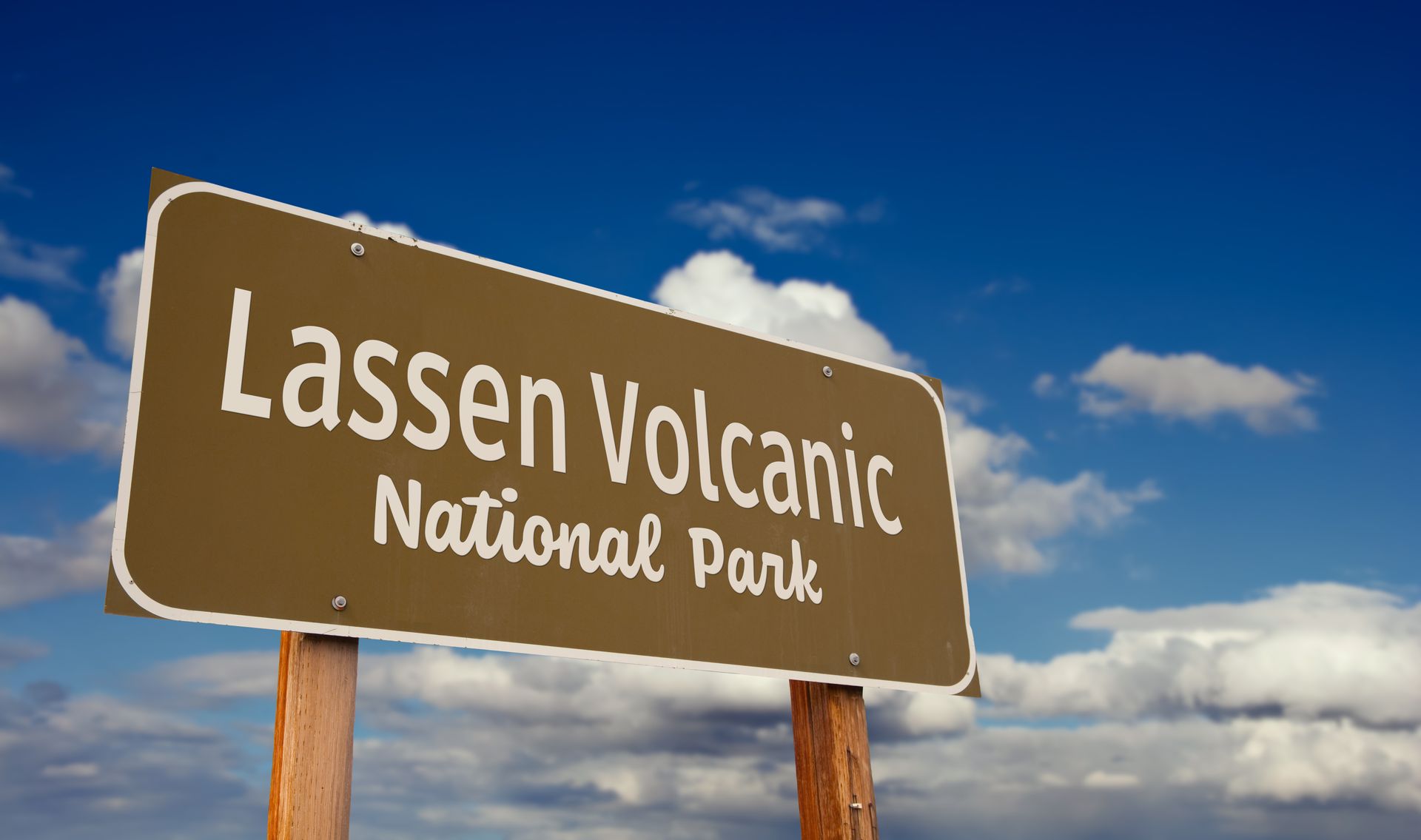 Lassen Volcanic National Park sign against a blue sky with clouds.d