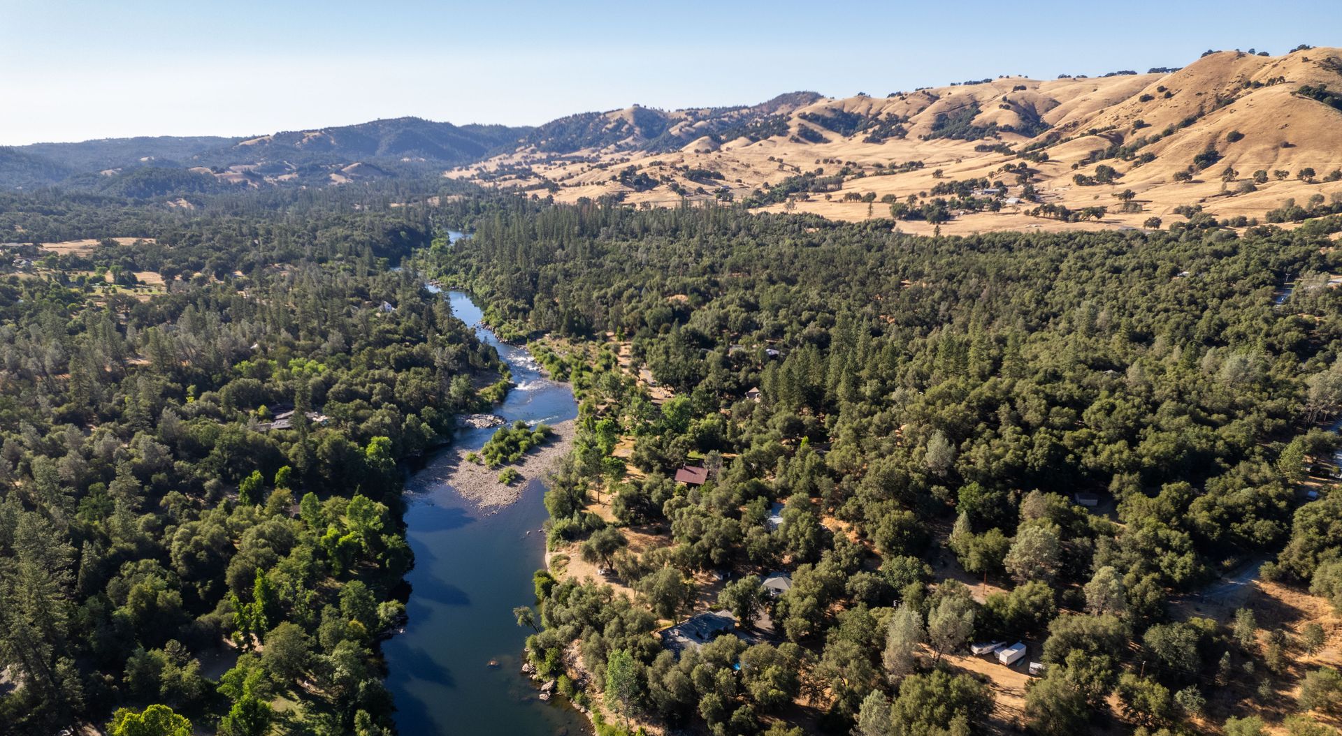 An aerial view of a river surrounded by trees and mountains.