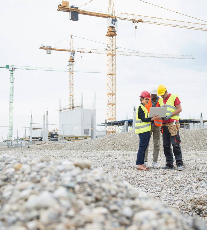 civil engineers with large cranes in background