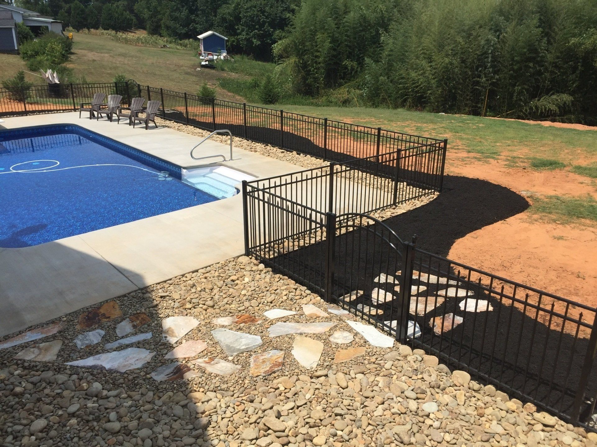 Stone Walkway Surrounded by Gravel Leading Through Gate to Pool Area
