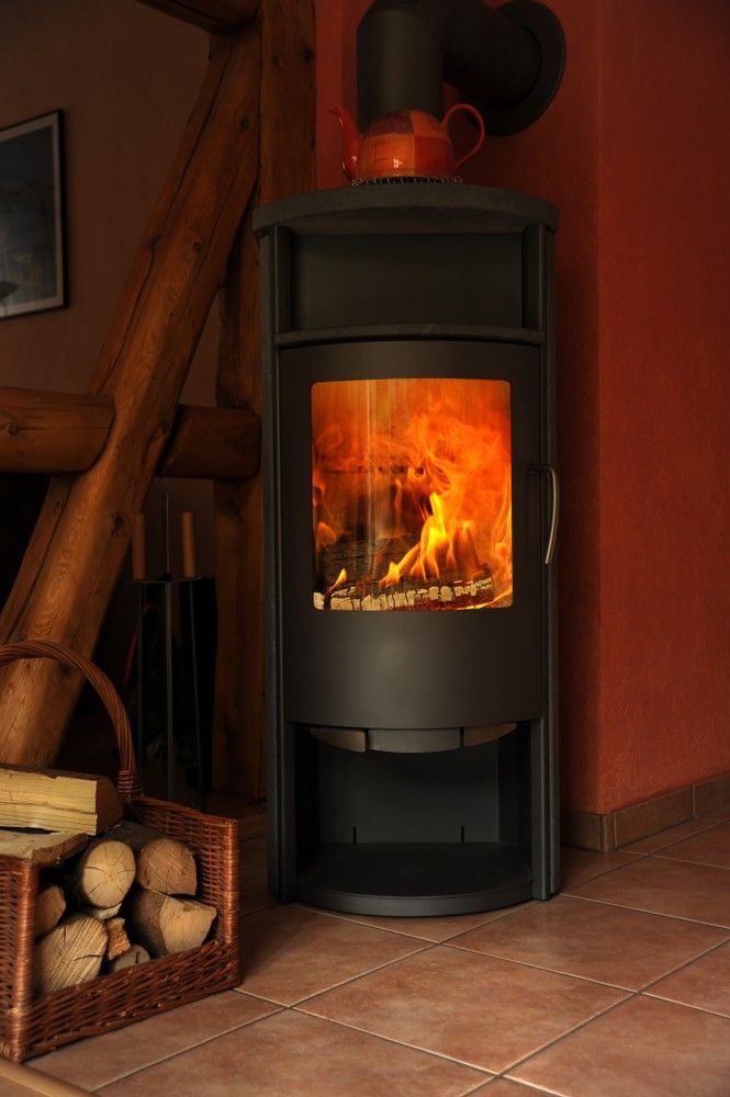 A Wood Stove is Sitting in a Living Room Next to a Basket of Logs — Ryno's Plumbing Group in Lakewood, NSW