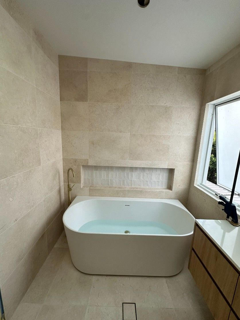 A Bathroom With a Large Bathtub and a Window — Ryno's Plumbing Group in Wauchope, NSW