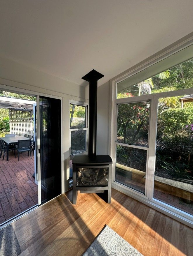 A Living Room With a Fireplace and Lots of Windows — Ryno's Plumbing Group in Lakewood, NSW