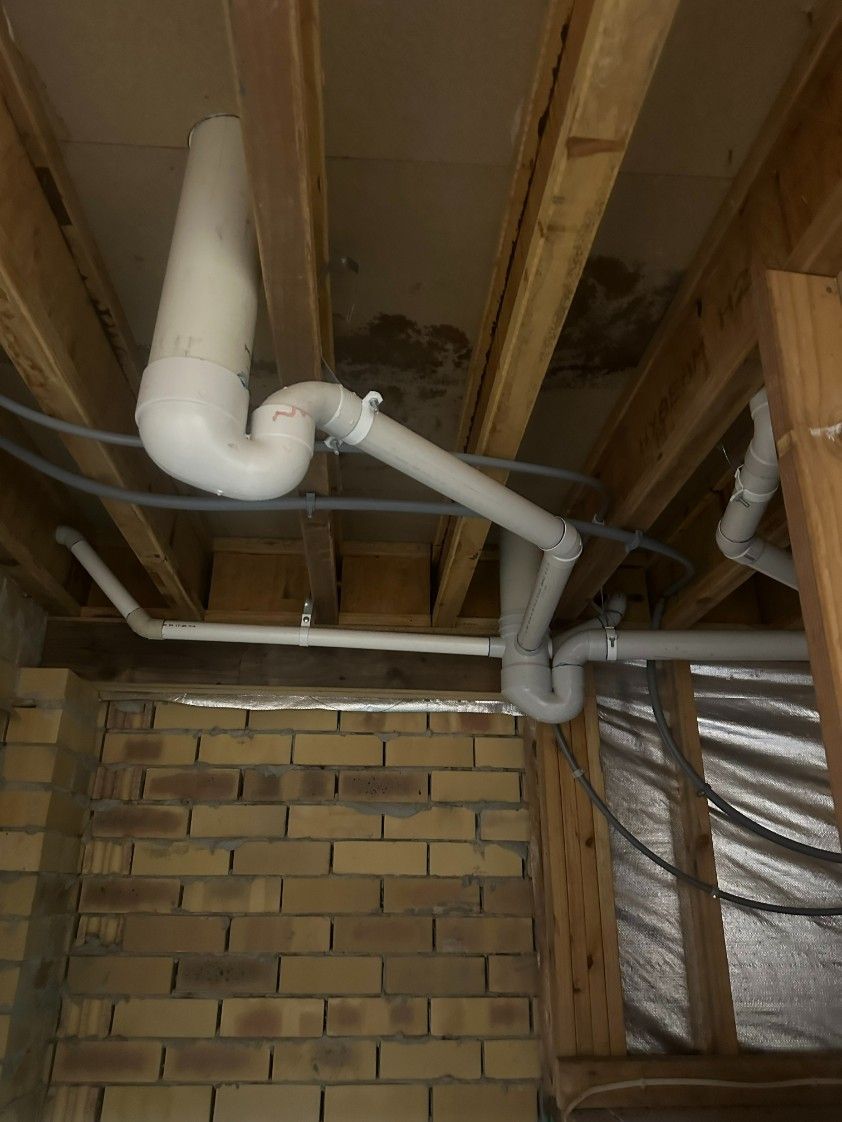 A Bunch of Pipes Are Hanging From the Ceiling of a Building — Ryno's Plumbing Group in Lakewood, NSW