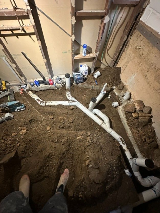 A Person is Standing in the Dirt Next to a Bunch of Pipes — Ryno's Plumbing Group in Lakewood, NSW
