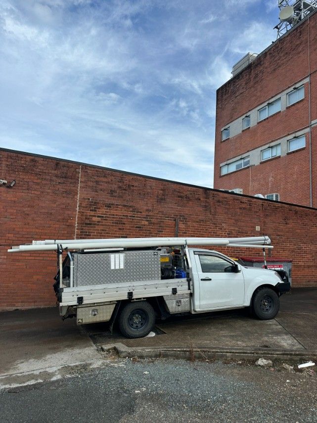 A White Truck is Parked in Front of a Brick Building — Ryno's Plumbing Group in Taree, NSW