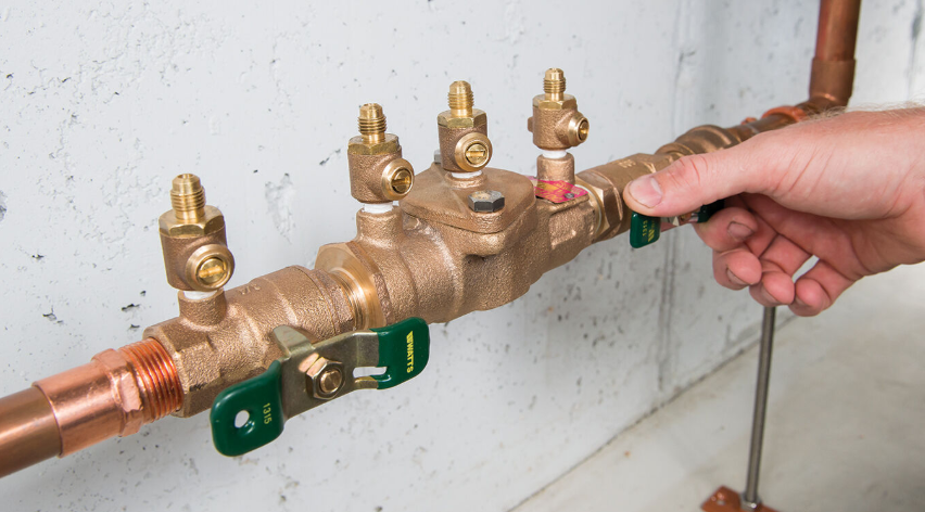 A Person Wearing Green Gloves is Cleaning a Sink Pipe — Ryno's Plumbing Group in Lakewood, NSW