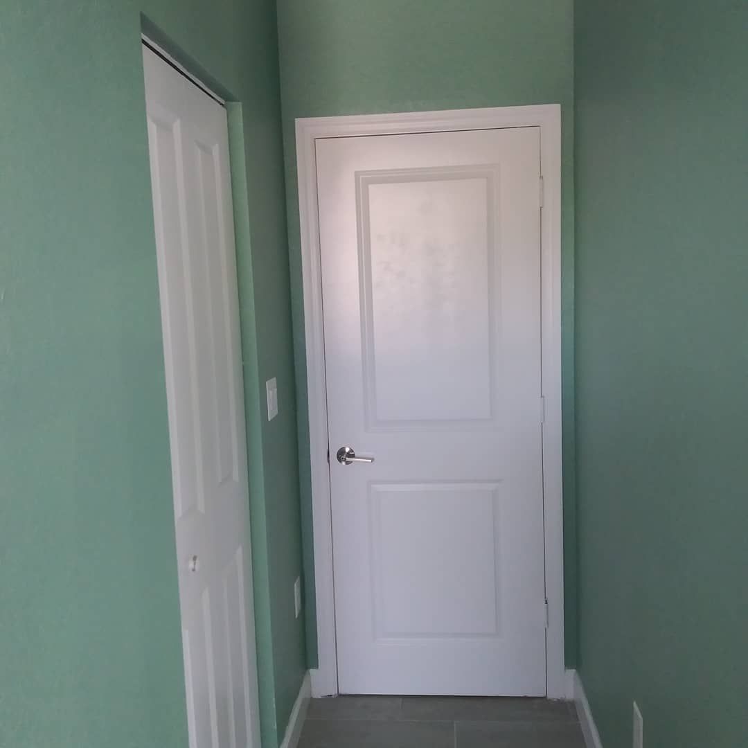 A hallway with green walls and a white door