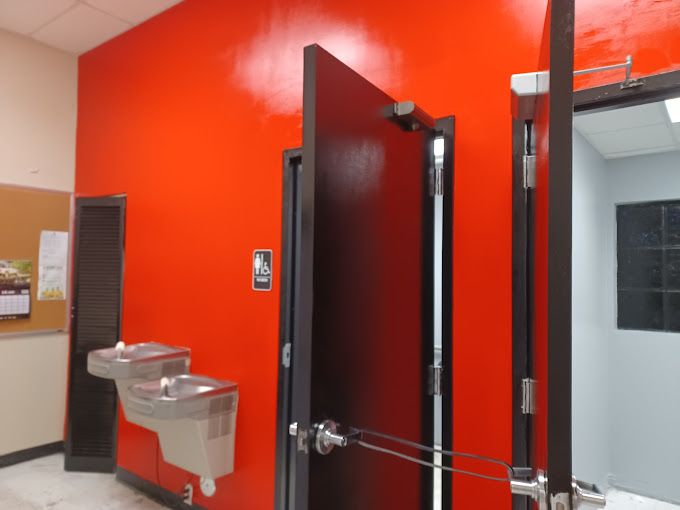 A bathroom with red walls and a black door