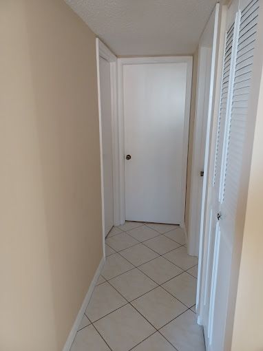 A hallway with a tiled floor and a white door.