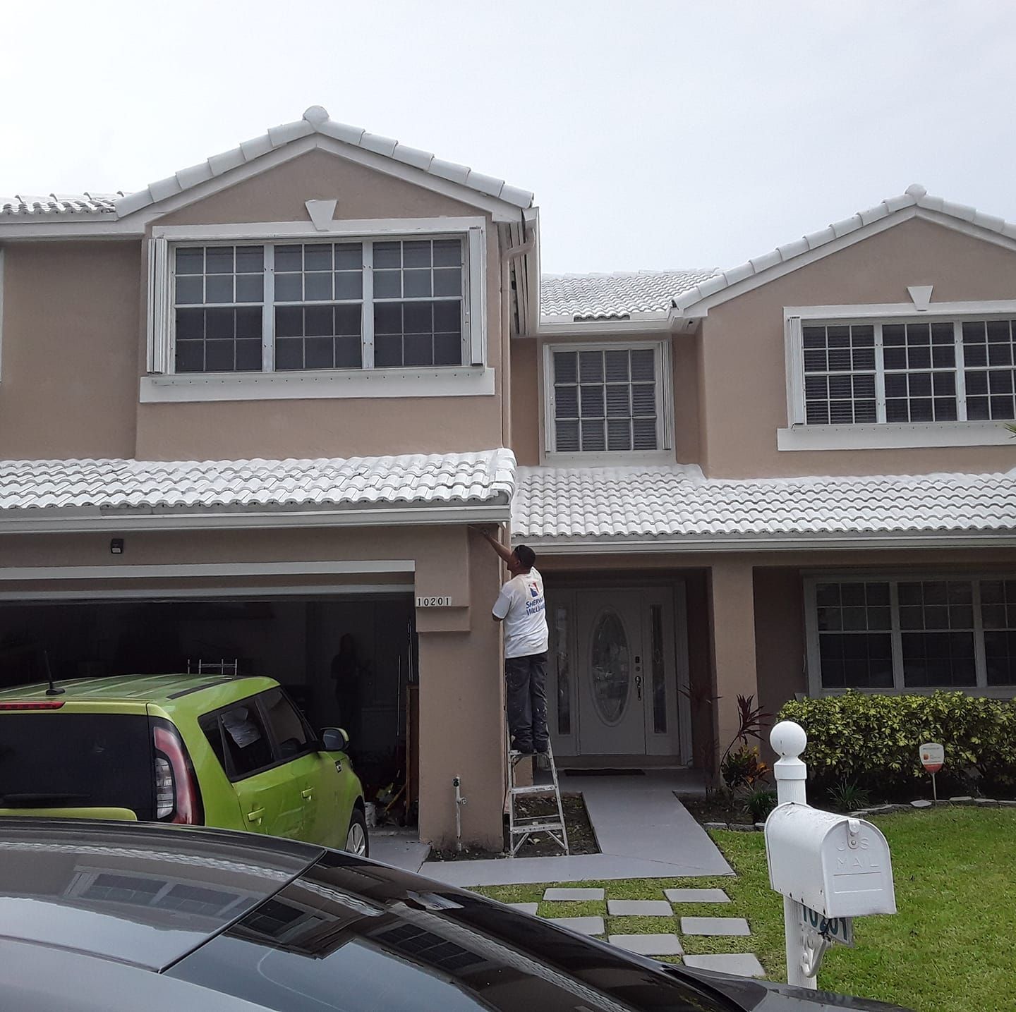 A man on a ladder is painting the side of a house